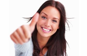 Woman smiling after teeth whitening, showing thumbs up
